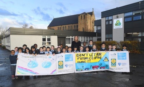 Pupils and teacher from St Mungos holding big banner in playground